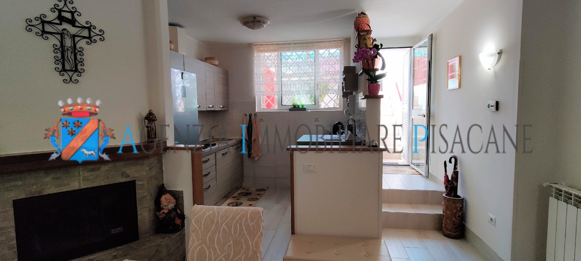 Sala con camino e cucina a vista - Agenzia Immobiliare & Architettura Pisacane